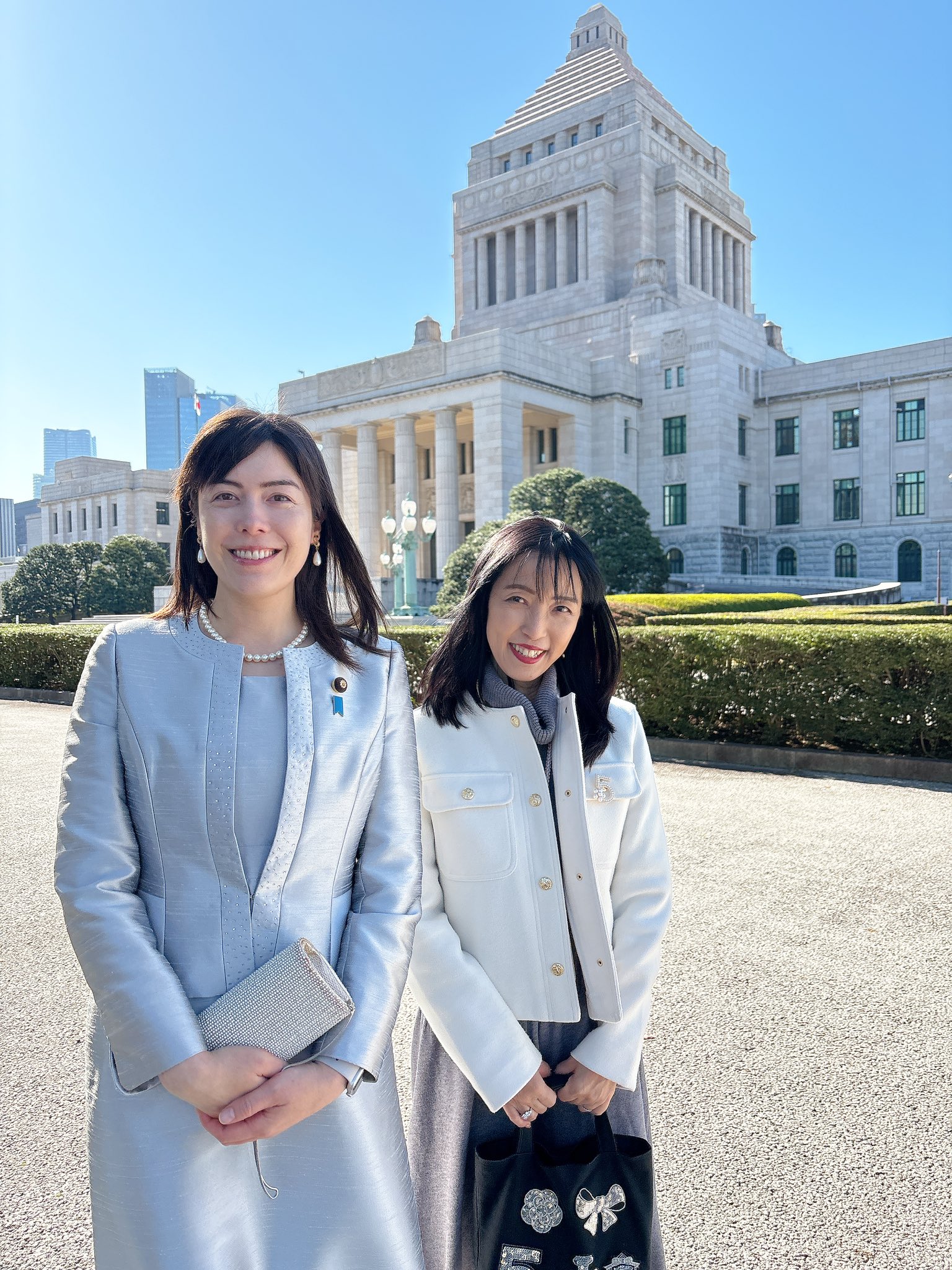 小野田紀美(左)在就職典禮上身穿銀色連衣裙。